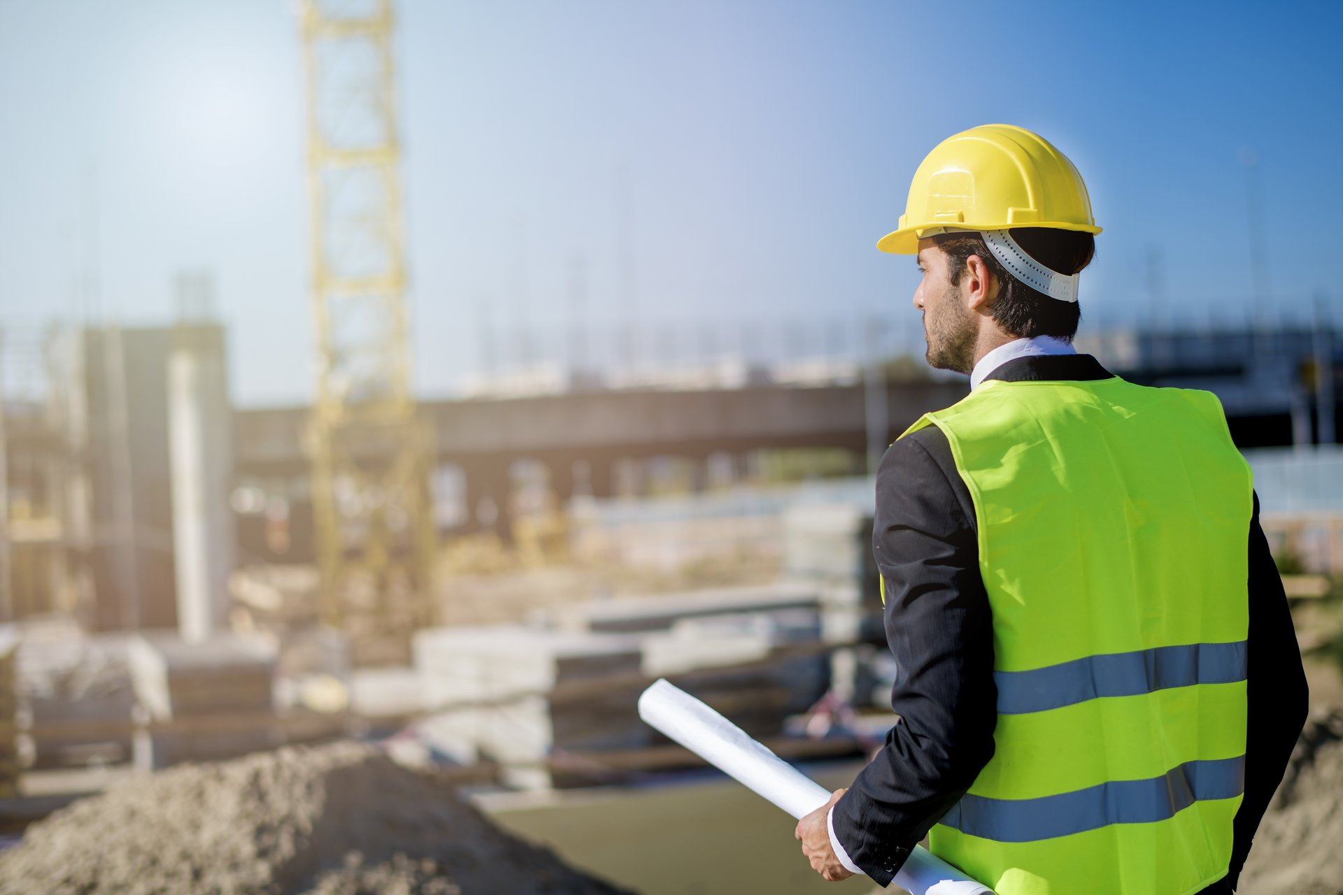 Executive reviewing blueprints at crane construction site