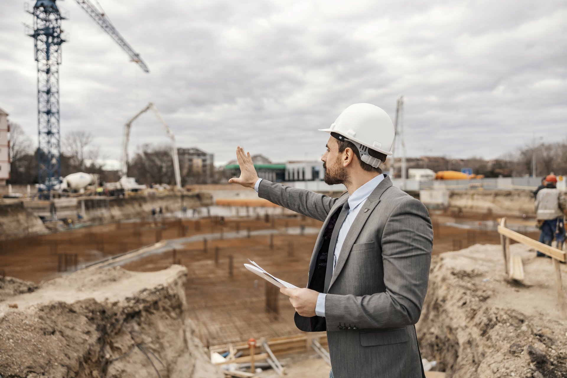 Executive in hard hat directing operations at construction site