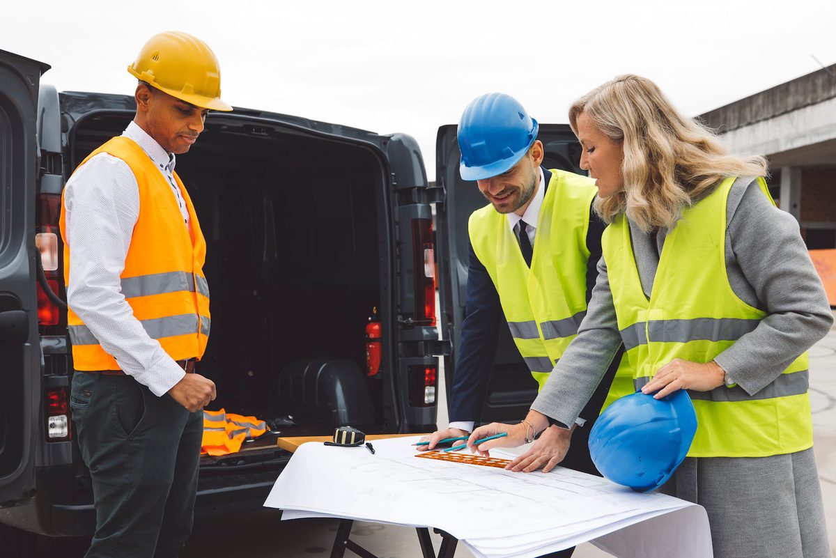 Construction crew morning huddle reviewing plans at job site