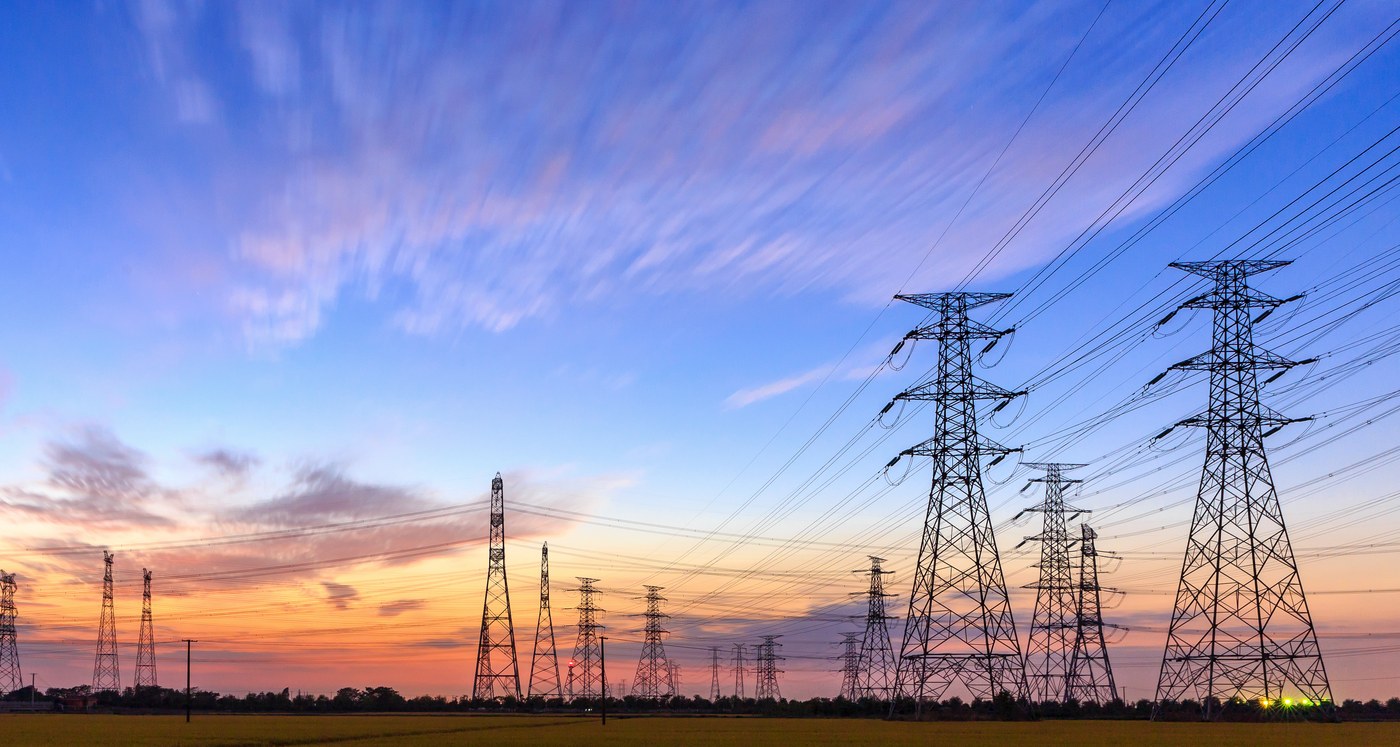 High voltage transmission towers along an energy corridor at dusk