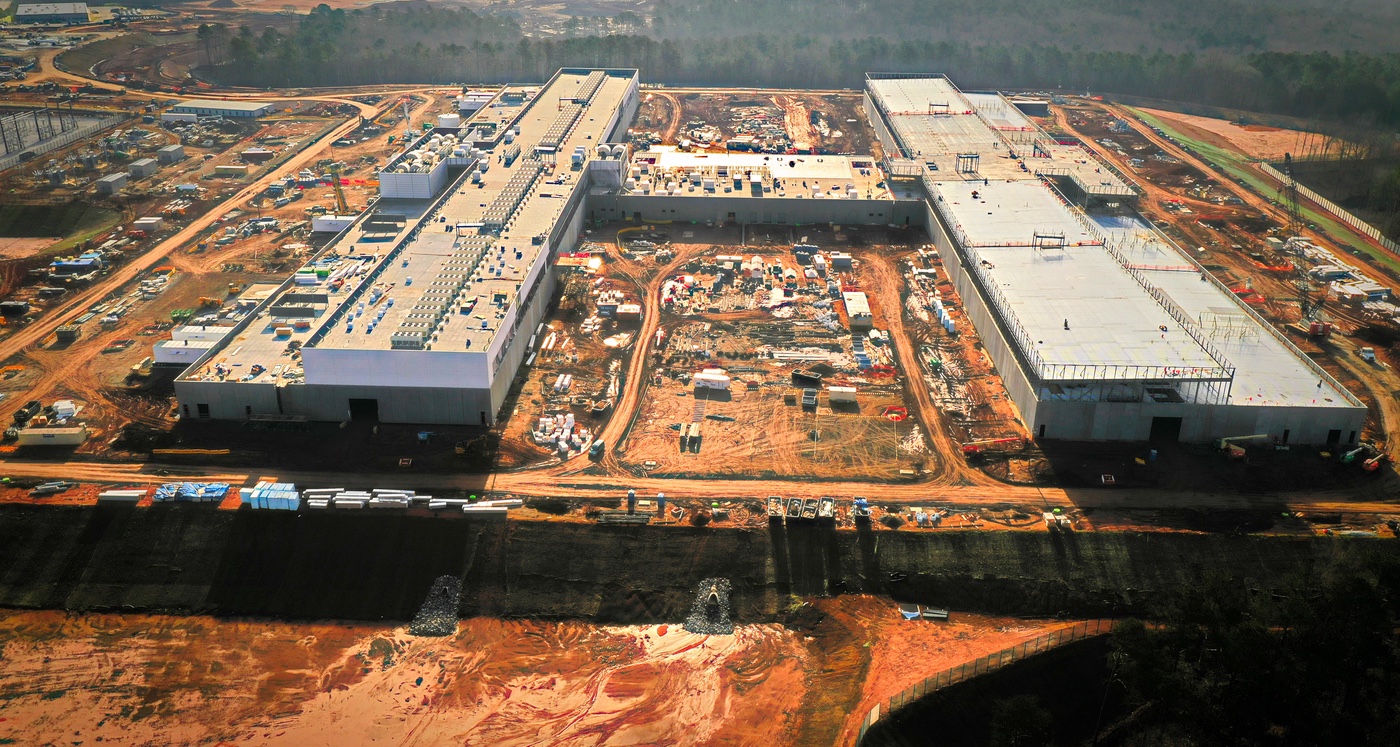 Aerial view of a large data center campus under construction, graded pads and site roads around the buildings