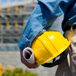 A man holding on to his yellow hard hat.