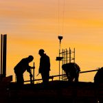 A group of men working on the top of a building.