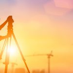 A tripod is in the foreground with a sunset behind it.