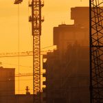 A crane is in the distance with buildings behind it.