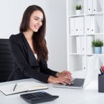 A woman sitting at her desk working on a laptop.