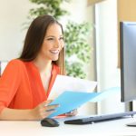 A woman sitting at her desk holding papers.