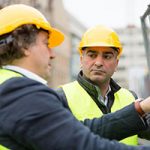 Two men in yellow hard hats and jackets.