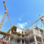 A building under construction with several cranes in the background.