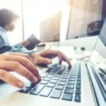 Person typing code on laptop computer.