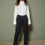 Woman in white shirt and pinstripe pants.