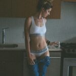 Woman in Calvin Klein underwear in kitchen.