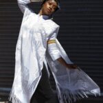 Woman in white lace dress and headwrap.